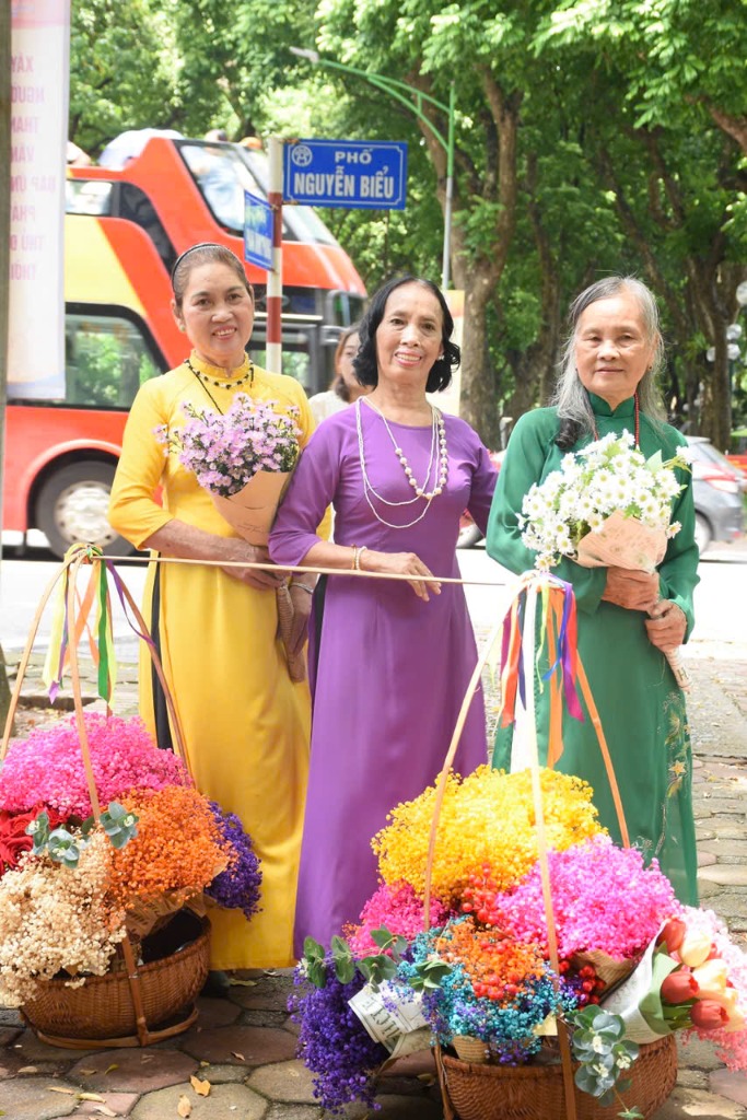 Các bà, các cô rạng rỡ trong tà áo dài bên gánh hoa tươi trên phố mùa thu Hà Nội
